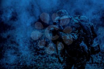 Commando soldier, army special operations fighter, elite troops sniper in camo uniform, carrying tactical backpack, aiming weapon, shooting from rifle, watching through optical sight at night mission