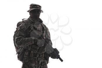 Army infantryman, commando rifleman, special forces shooter in camouflage uniform, aiming service rifle with collimator sight, shooting in firefight, carrying tactical backpack, isolated studio shoot