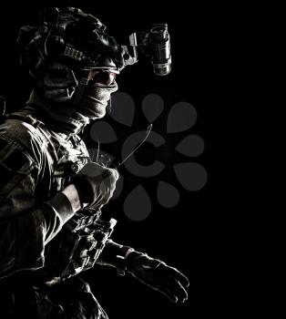 Army elite commando, professional mercenary, counter-terrorist tactical team fighter in combat helmet, equipped night-vision device, creeping in darkness with service knife in hand, studio shoot