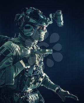 Army special operations soldier, security service fighter, commando shooter equipped modern ammunition, wearing combat helmet, mask and glasses, carefully sneaking in darkness with handgun in hand