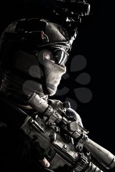 Shoulder portrait of army elite troops sniper, anti-terrorist tactical team marksman wearing helmet with thermal imager, hiding face behind mask, armed rifle with optical scope, studio shoot on black