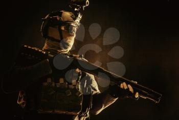 Shoulder portrait of army elite troops soldier, anti-terrorist tactical team wit shotgun, helmet with thermal imager, hiding face behind mask, armed rifle with optical scope, studio shoot on black