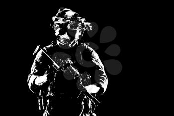 Army elite soldier with hidden behind mask and glasses face, in full tactical ammunition, equipped night vision device, radio headset, looking aside, armed short barrel rifle studio contour shot