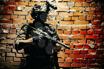 Shoulder portrait of army elite troops soldier, anti-terrorist tactical team, helmet with thermal imager, hiding face behind mask, armed assault rifle