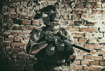 Army special forces tactical group fighter in cqb mission, using radio headset, looking through four lens night-vision, thermal imaging device on helmet, armed small submachine gun with silencer