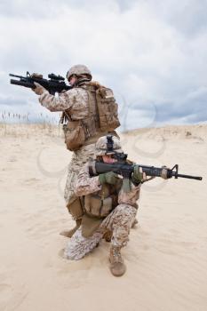 two US marines aim at different directions covering each other