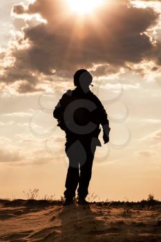 Silhouette of young soldier in military helmet against the sun