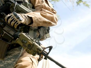 US soldier in camouflage uniform holding his rifle