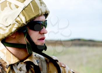 British soldier with the reflection of UK flag in glasses looking forward