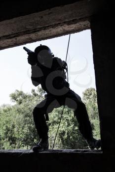 Spec ops soldier in face mask during rope exercises with weapons