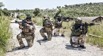 SEALs team fighters, army special operations forces soldiers mowing with caution on road, kneeling, aiming weapon and covering comrades. Commando infantry patrolling territory, observing area
