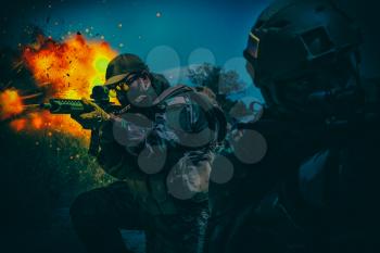 Army special operations forces soldiers, Navy SEALs team armed assault rifle, rushing on battlefield with fiery explosion, attacking enemy at night. Commando rifleman covering comrade with gunfire