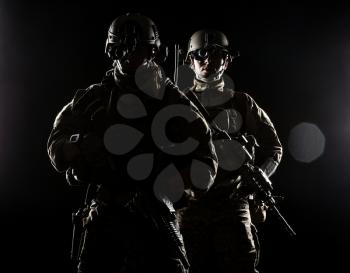 United States Army rangers with assault rifles on dark background
