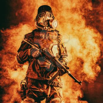 Futuristic nazi soldier in fire and smoke gas mask and steel helmet with schmeisser handgun