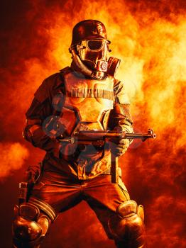 Futuristic nazi soldier in fire and smoke gas mask and steel helmet with schmeisser handgun
