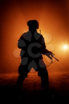 Silhouette of modern infantry soldier, elite army fighter in tactical ammunition and helmet, standing with assault service rifle in hands