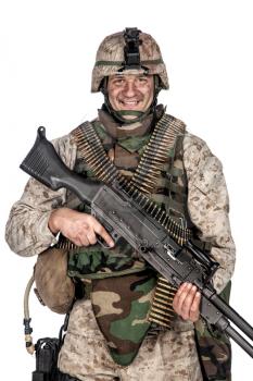 Studio shoot of army, marine machine gunner in camouflage combat uniform and body armor, standing with machine gun, isolated on white