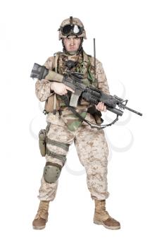 Full length studio shoot of marine infantry, commando soldier in full protective ammunition, standing with service rifle equipped grenade launcher and looking at camera, isolated on white background