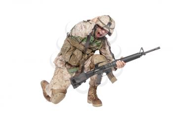 Army soldier in camo uniform, armed with assault rifle and machine gun, crouching to ground, holding helmets and covers ears with hands isolated on white studio shoot Grenade or bomb explosion
