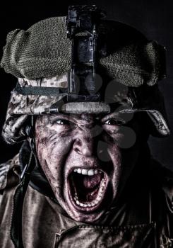 Close up portrait of aggressive screaming army soldier, attacking with mad yelling commando, roaring and grimacing marine in camouflage helmet with sweaty, dirty face studio shoot on black background