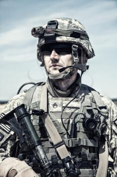 Portrait of United states airborne infantry man with arms, camo uniforms dress. Combat helmet on, tactical light, radio microphone on his mouth