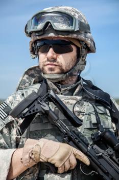 Portrait of United states airborne infantry marksman with arms, camo uniforms dress. Combat helmet on, unshaven