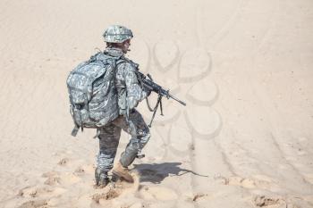 Portrait of United states airborne infantry machinegunner, camo uniforms dress and backpack. Moving desert, long range mission, back view, full body