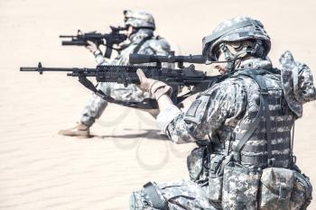Team of United states airborne infantry men in action in the desert, side view cropped