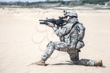 United states airborne infantry man in action in the desert, kneeling position, side view
