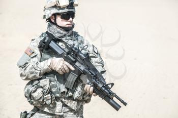 United states airborne infantry corporal with arms, camo uniforms dress. Combat helmet on, tactical light, front view cropped portrait