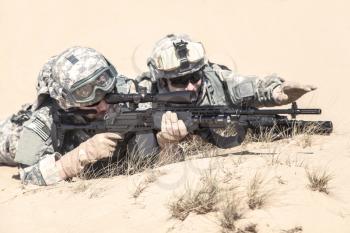 Team of United states airborne infantry men in action in the desert, lying pair of spotter and marksman