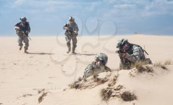 Team of United states airborne infantry men with weapons in action in desert