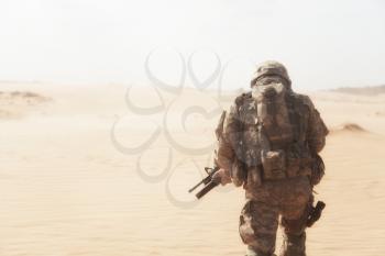 Portrait of United states airborne infantryman moving through desert storm. Cropped portrait, overcome difficulties concept