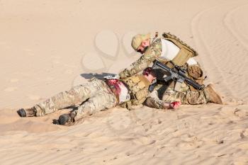 US Army Special Forces soldier medic treating the wounds of injured in the desert