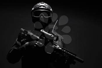 Spec ops police officer SWAT in black uniform and face mask studio shot