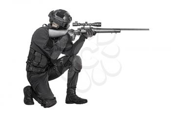 Studio shot of swat operator with sniper rifle wearing black uniforms pointing enemy. Tactical helmet gloves, eyewear and telescopic sight, kneeling position