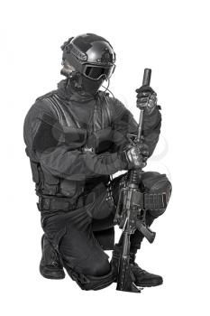 Studio shot of swat operator mounting suppressor on sniper rifle. Tactical helmet and gloves, eyewear and telescopic sight, knee pads