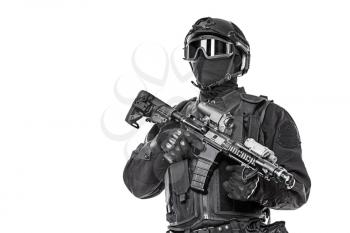 Studio shot of swat operator with assault rifle. Tactical helmet gloves, eyewear. Security forces concept