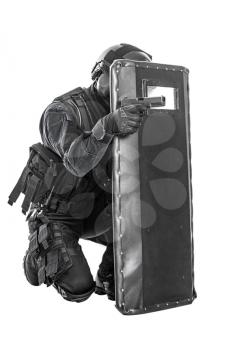Studio shot of swat police special forces aiming criminals with pistol sitting hiding behind ballistic shield. Isolated on white