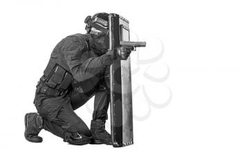 Studio shot of swat police special forces aiming criminals with pistol sitting hiding behind ballistic shield. Isolated on white