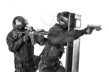 Studio shot of swat police special forces aiming criminals with rifle pistol hiding behind ballistic shield. Isolated on white side view