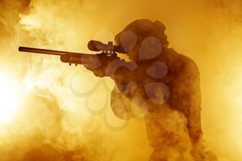 Studio shot of swat police operator with sniper rifle in black uniforms aiming criminals terrorists Fire smoke screen background. Punishment concept