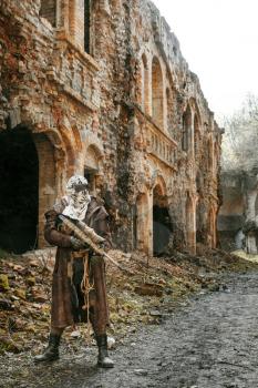 Nuclear post-apocalypse. Sole survivor in tatters and gas mask on the ruins of the destroyed city