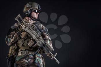 United states Marine Corps special operations command Marsoc raider with weapon. Studio shot of Marine Special Operator half-turning black background