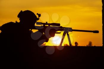Army sniper with large-caliber sniper rifle seeking killing enemy. Silhouette on sky background. National security ensured, servicemen on guard