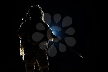 Army sniper with big rifle standing on black background. Backlit contour silhouette shot. Invisible death concept