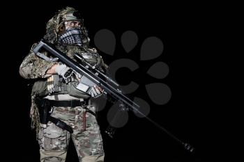 Army sniper with big rifle standing on black background