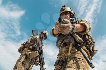 US Army Rangers pointing weapons to the camera detaining person. Low angle view
