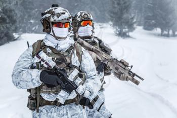 Winter arctic mountains warfare. Action in cold conditions. Troopers with weapons in forest somewhere above the Arctic Circle