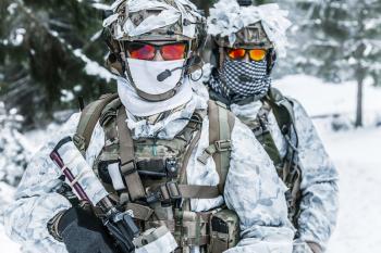 Winter arctic mountains warfare. Action in cold conditions. Soldiers with weapons in forest somewhere above the Arctic Circle